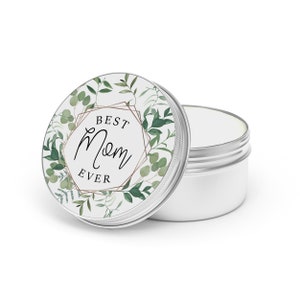 May include: A silver tin with a white lid featuring a green floral design and the text "Best Mom Ever".
