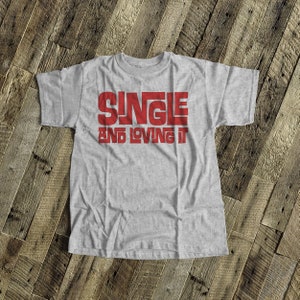 May include: Gray t-shirt with the text "SINGLE AND LOVING IT" in red.