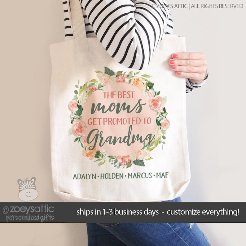 May include: A white tote bag with a floral wreath design and the text "The Best Moms Get Promoted to Grandma". The names "Adalyn, Holden, Marcus, and Maf" are listed below the wreath.