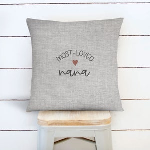 May include: Gray throw pillow with the text "MOST-LOVED nana" in black lettering and a small red heart.