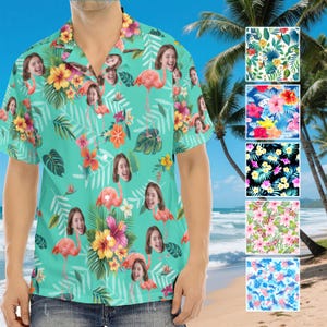May include: A short-sleeved, button-down shirt with a turquoise background. The shirt features a repeating pattern of pink flamingos, tropical flowers, and a smiling face. Additional patterns are displayed on the right side of the image.