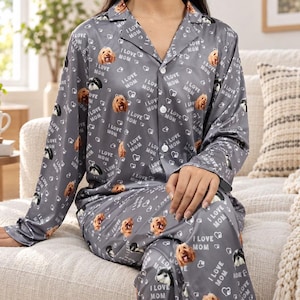 Pode incluir: Um conjunto de pijama cinza de manga comprida com um padrão repetitivo de rostos de cães, pequenos corações brancos e o texto I LOVE MOM. A camisa abotoada tem uma gola entalhada e as calças a condizer têm um corte descontraído.