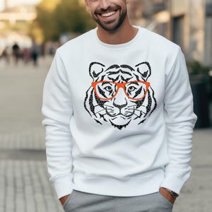 May include: White sweatshirt featuring a black and white tiger wearing red glasses graphic print.