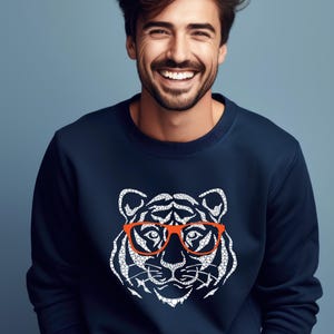 May include: A navy blue sweatshirt featuring a white graphic of a tiger wearing red-rimmed glasses.