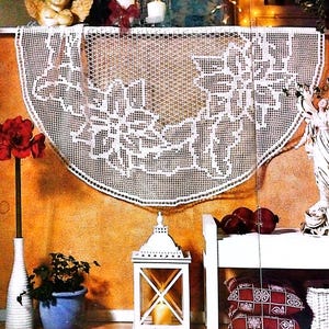 May include: White crocheted half-circle doily with a floral design, hanging on a wall with a brown background. A white vase with a red flower is on the left side of the image. A white lantern with a candle inside is on the right side of the image.