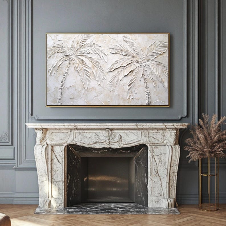 May include: A white textured painting of two palm trees with a gold frame. The painting is hanging above a white marble fireplace.