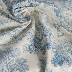May include: A white fabric with a blue toile pattern featuring a repeating design of trees, flowers, and figures. The fabric has a soft, textured feel and is perfect for crafting projects.