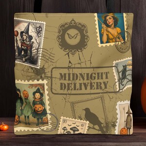 May include: A beige tote bag with black handles featuring a vintage Halloween design. The design includes postage stamp illustrations, a raven, and the words "MIDNIGHT DELIVERY". A carved jack-o'-lantern and string lights are in the background.