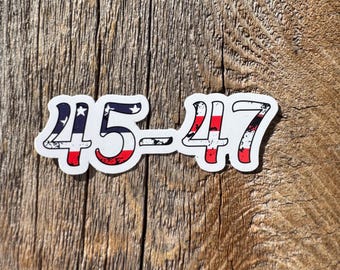 May include: A white sticker with the numbers "45-47" in red, white, and blue, resembling the American flag. The sticker is on a wooden surface.