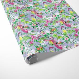 a gift wrapped in vibrant Florida-themed wrapping paper with playful illustrations of alligators, palm trees, and tropical flowers on a lavender background. A crisp white ribbon tied into a bow adds an elegant touch to the lively gift wrap.