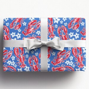 a gift wrapped in vibrant, preppy wrapping paper featuring bold red lobsters and white flowers on a blue background. The lively design is complemented by a crisp white ribbon, adding a touch of elegance to the playful gift wrap.