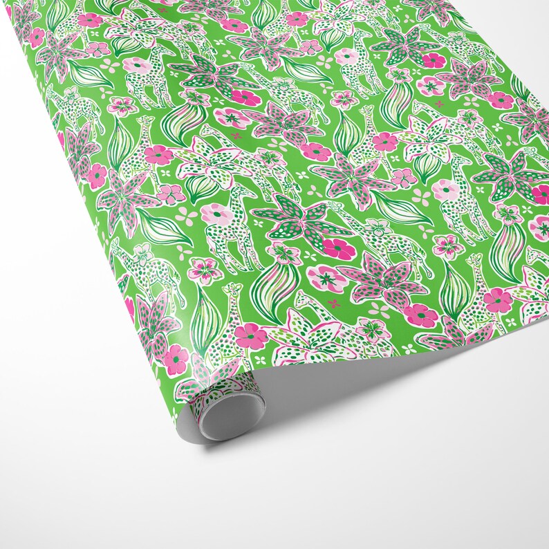 a gift wrapped in vibrant, tropical-themed wrapping paper featuring pink and white flowers and playful giraffes on a bright green background. A crisp white ribbon tied into a bow adds a classic, elegant touch to the lively and fun design.