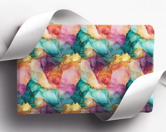 May include: A rectangular gift wrap with a vibrant abstract design. The pattern features blended shades of teal, pink, orange, and purple with gold accents. A white ribbon curls around the edge of the wrap, adding a decorative touch.