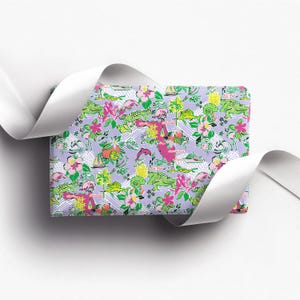 a gift wrapped in vibrant Florida-themed wrapping paper with playful illustrations of alligators, palm trees, and tropical flowers on a lavender background. A crisp white ribbon tied into a bow adds an elegant touch to the lively gift wrap.