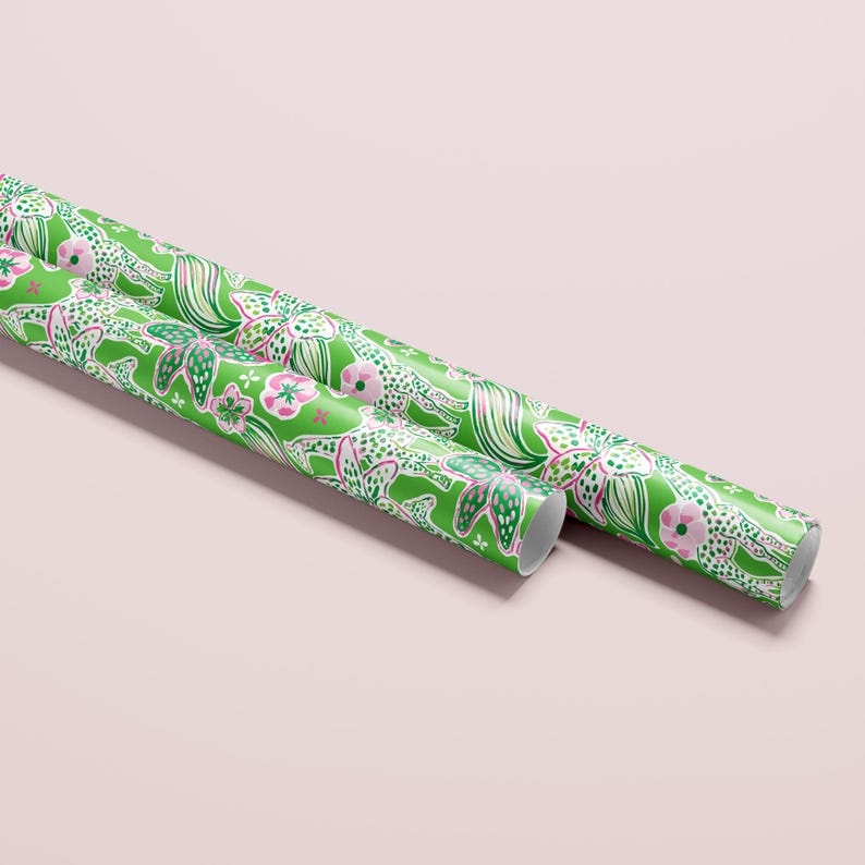 a gift wrapped in vibrant, tropical-themed wrapping paper featuring pink and white flowers and playful giraffes on a bright green background. A crisp white ribbon tied into a bow adds a classic, elegant touch to the lively and fun design.