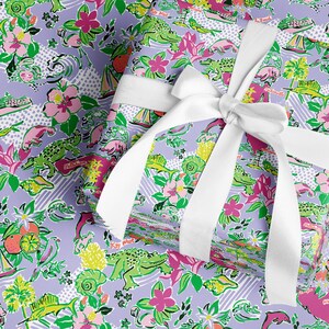 a gift wrapped in vibrant Florida-themed wrapping paper with playful illustrations of alligators, palm trees, and tropical flowers on a lavender background. A crisp white ribbon tied into a bow adds an elegant touch to the lively gift wrap.