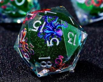 May include: A clear, multi-faceted D20 die with a green glitter interior. The die features a blue and purple octopus design and white numbers. Other dice are visible in the background.
