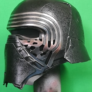 May include: A black and silver helmet with a textured surface and a detailed design. The helmet has a visor and a chin guard.