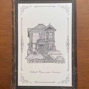 Op de afbeelding: Zwart-wit illustratie van een Victoriaans huis, getiteld "Halliwell Manor from Charmed", in een decoratief kader. De afbeelding staat op een witte achtergrond en is geplaatst in een versleten, donkerbruine boekomslag.