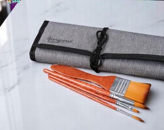 May include: A set of paint brushes with wooden handles and synthetic bristles, alongside a gray canvas brush roll. The brush roll is secured with a black cord and features the name "Giorgione". The brushes vary in size and shape.