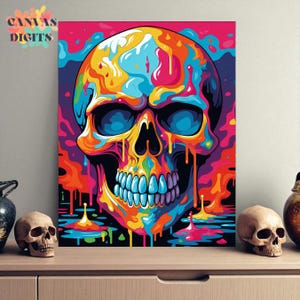 Op de afbeelding: Een levendige, kleurrijke schedelkunstprint met een psychedelisch ontwerp. De schedel heeft een regenboog aan kleuren, waaronder blauw, geel, oranje en paars. Het kunstwerk wordt op een muur weergegeven, met de tekst "CANVAS DIGITS".