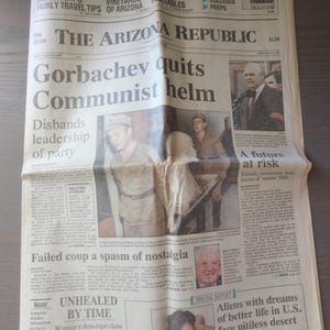 May include: A black and white newspaper front page with the headline "Gorbachev quits Communist helm". The article discusses the failed coup attempt in the Soviet Union and the potential for ethnic and economic unrest if the union falls apart.