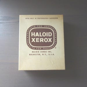 May include: A vintage box for Haloid Xerox products for photography. The box is beige with brown text and a brown circle logo that says "Products for Xerography Haloid Xerox Products for Photography".
