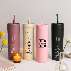 Könnte beinhalten: Vier Becher mit mattem Finish und passenden Strohhalmen in Mauve, Beige, Hellrosa und Schwarz. Jeder Becher trägt eine individuelle schwarze Beschriftung: Michele mit Bridesmaid, Darlen, Brian mit einem großen B und Michele mit Bride.
