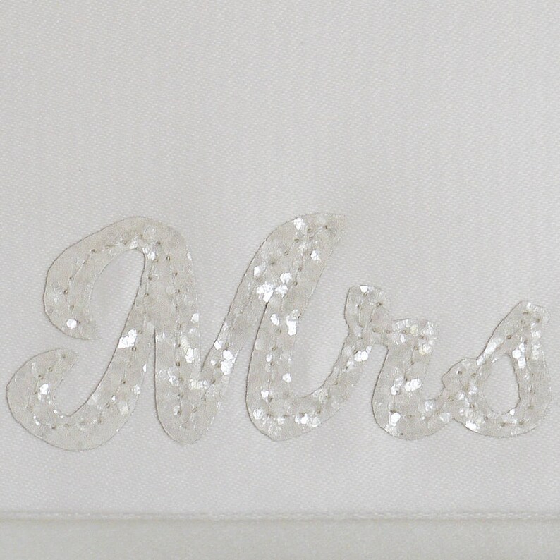 Close up detail of ivory satin MRS bridal clutch for wedding day.  It can be personalised with the brides new surname, made from ivory glitter.