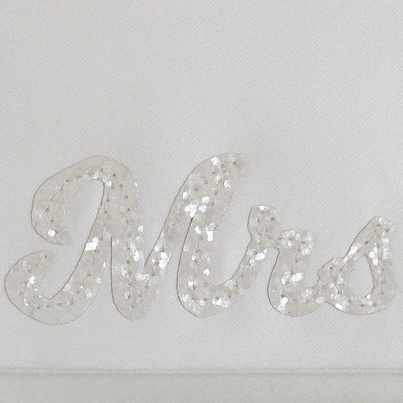 Close up of ivory satin MRS bridal clutch for wedding day.  It can be personalised with the brides new surname, made from ivory glitter.