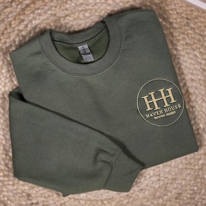 May include: A dark green sweatshirt with a gold embroidered logo that says "Haven House Interior Design" in a circle.