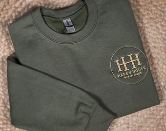 May include: A dark green sweatshirt with a gold embroidered logo that says "Haven House Interior Design" in a circle.