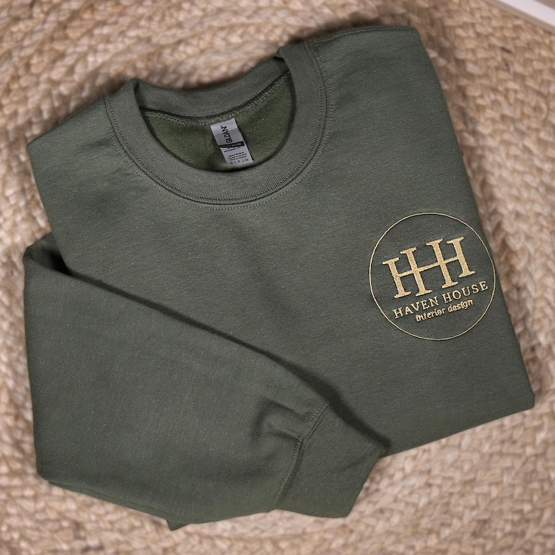 May include: A dark green sweatshirt with a gold embroidered logo that says "Haven House Interior Design" in a circle.