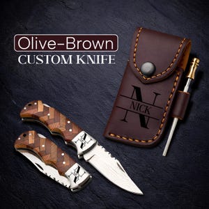 May include: An olive-brown custom knife with a wooden handle and a stainless steel blade. The knife is accompanied by a brown leather sheath with the name "NICK" engraved on it. A sharpening steel is also included.