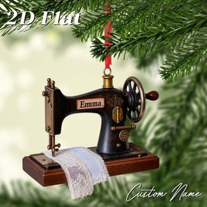 Könnte beinhalten: Ein Weihnachtsornament in Form einer Nähmaschine im Vintage-Stil. Es ist dunkelbraun mit goldenen Akzenten und einem kleinen Stück weißer Spitze. Der Name "Emma" ist auf der Maschine aufgedruckt. Hängt an einem roten Band.