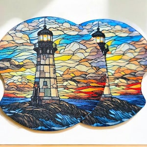 May include: Two stained glass style coasters featuring a lighthouse with a sunset and ocean waves in the background. The coasters are made of a durable material and are perfect for protecting your furniture from spills and scratches.