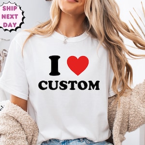 May include: White t-shirt with the text "I ♥ CUSTOM" in black and red. The heart symbol is red. The shirt is a crew neck style.