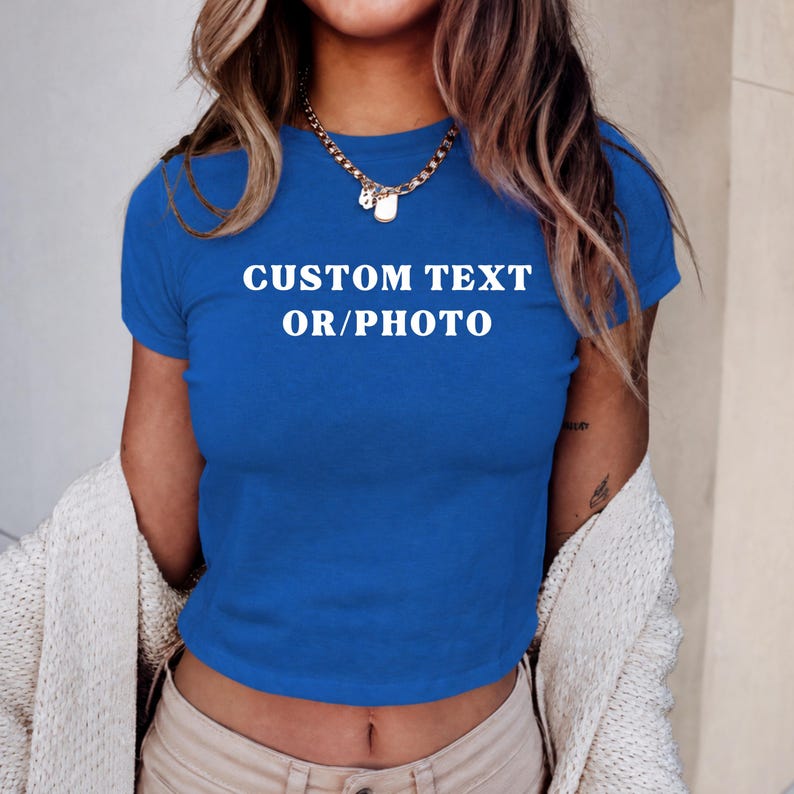 A woman wearing a blue cropped top with the text "CUSTOM TEXT OR/PHOTO" printed on it.