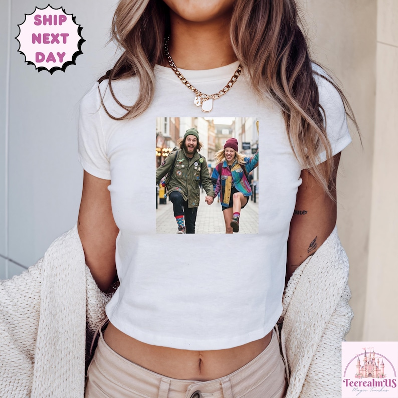 A person wearing a white t-shirt with a printed photo of two people walking down a street.