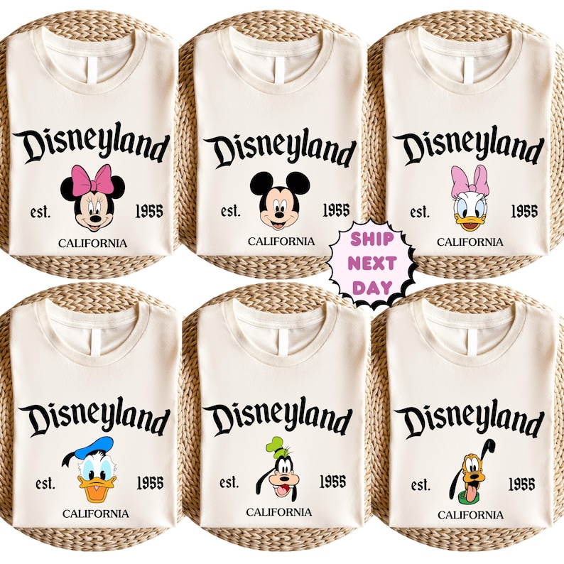 May include: Cream-coloured t-shirts featuring the Disneyland logo with various Disney character graphics. Each shirt has the text "est. 1955 CALIFORNIA". Characters include Minnie Mouse, Mickey Mouse, Daisy Duck, Donald Duck, Goofy, and Pluto.