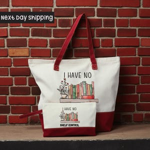 A white tote bag with a red handle and a smaller white bag with a red handle, both featuring illustrations of books and the text "I HAVE NO SHELF CONTROL".