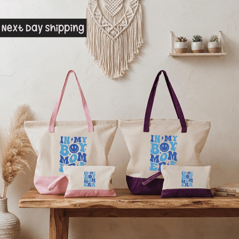 a set of two tote bags and a small bag on a wooden surface, with a wall decoration and some plants in the background.