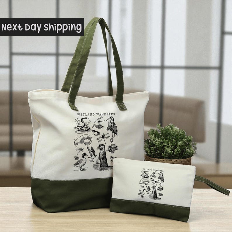 A large white tote bag with a green trim and a smaller white bag with a similar design, both featuring illustrations of various birds and wildlife, are displayed on a wooden surface.