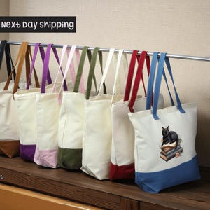 A row of colorful tote bags hanging on a rack, with a sign indicating next day shipping.