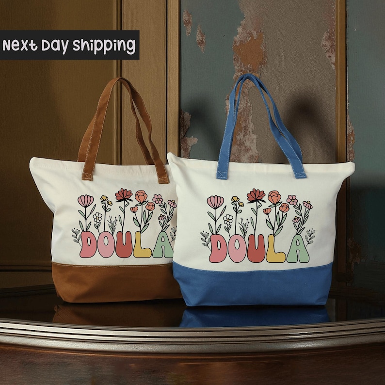 Two colorful tote bags with the word "DOULA" printed on them, placed on a wooden surface.