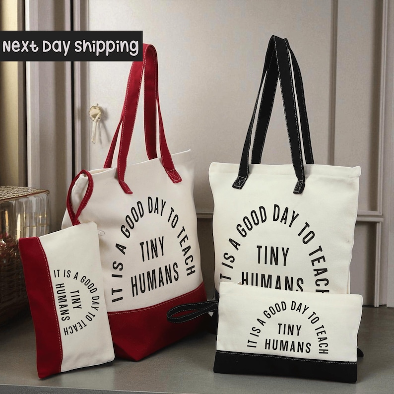 a collection of bags and accessories, including a red and white tote bag, a black and white tote bag, and a small red and white bag. The bags have a message printed on them that says "It is a good day to teach tiny humans".