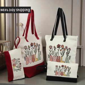 a collection of bags and accessories, including a red and white tote bag, a white tote bag, and a small black bag, all featuring the word "DOULA" printed on them.