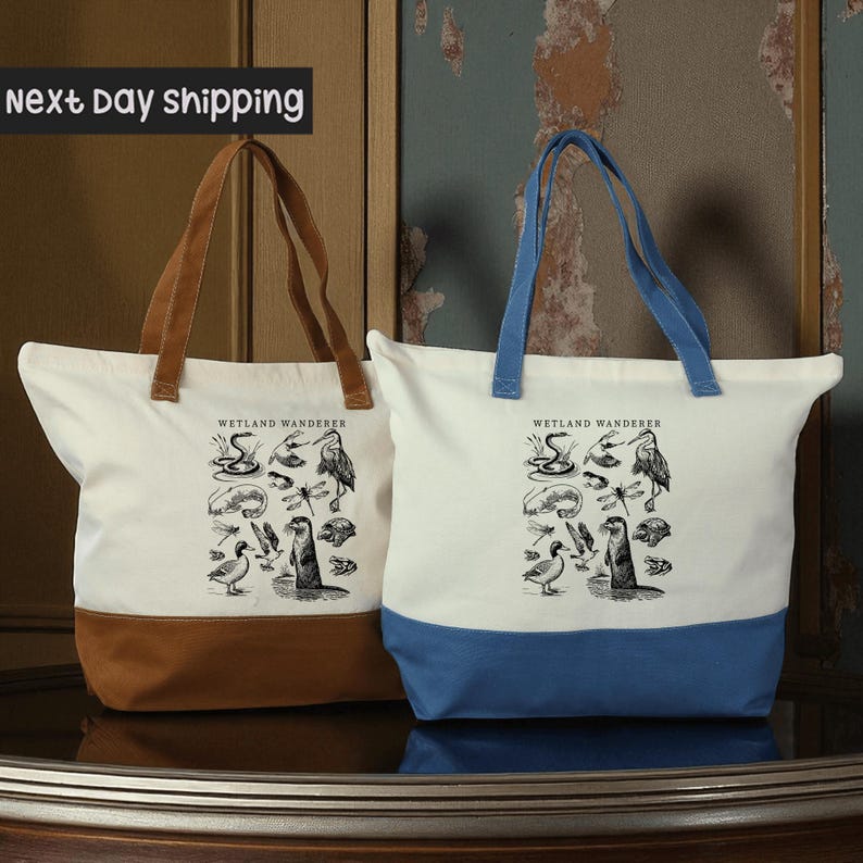 Two tote bags with illustrations of birds and wildlife printed on them, placed on a reflective surface against a weathered wall.
