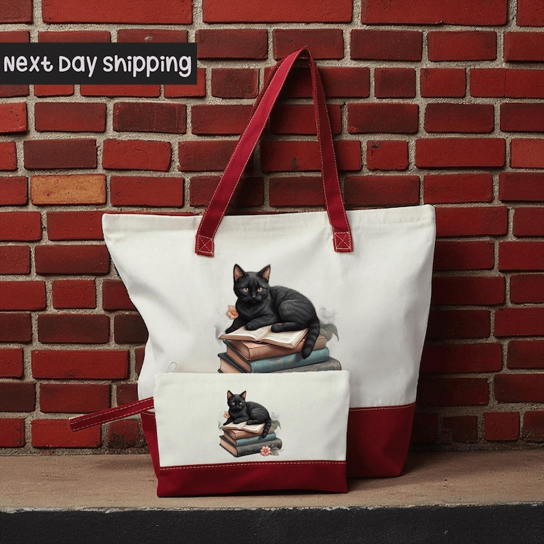 A large white tote bag with a red handle and a smaller white makeup bag with a cat design on it, both placed against a brick wall.