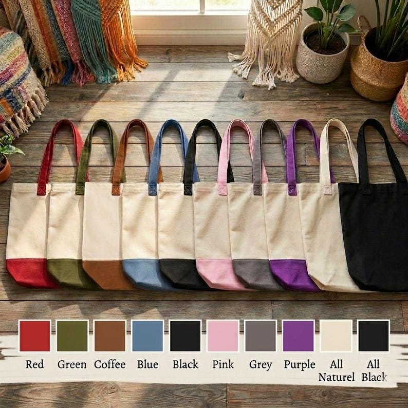A row of colorful tote bags in various colors, including red, green, blue, black, pink, grey, purple, and natural black, arranged on a wooden floor.